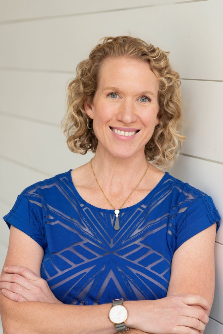 Heather Hukari smiling, arms crossed, in a cobalt blue top